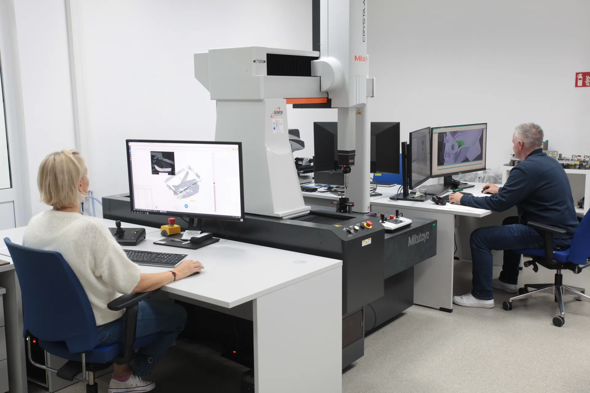 Maszyna współrzędnościowa Mitutoyo w laboratorium pomiarowym; po obu stronach operatorzy, na ekranach skan 3D i model CAD
